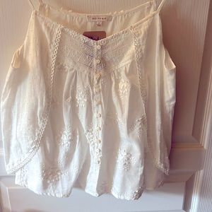 White cami tank with adjustable straps and intricate detail.